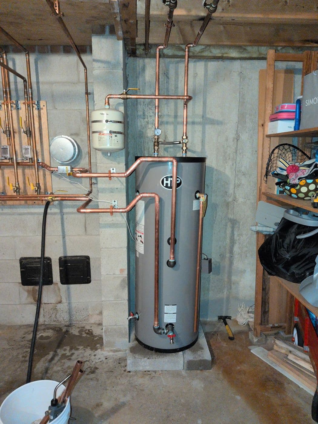 Indirect water heater tank with copper piping connecting to a zone manifold in a basement
