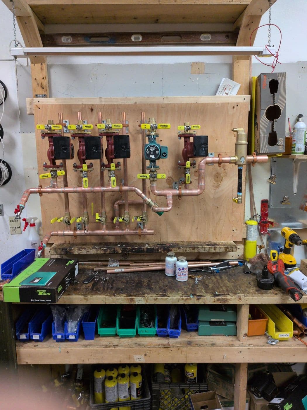 Four-circulator pump assembly built on a plywood panel with copper piping and isolation flanges